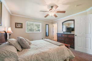 Carpeted bedroom featuring crown molding and a ceiling fan