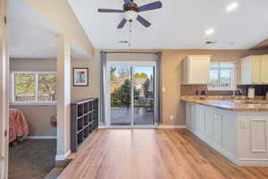 Kitchen with light stone countertops, light wood-style flooring, recessed lighting, backsplash, and white cabinetry