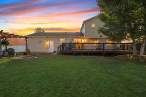 Back of property at dusk featuring a deck and a patio area