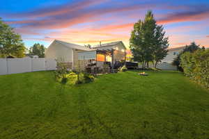 Back of house at dusk with a fenced backyard, a patio, and a ceiling fan