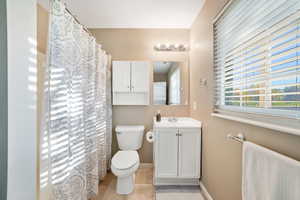 Full bath featuring vanity, a shower with shower curtain, and light tile patterned floors