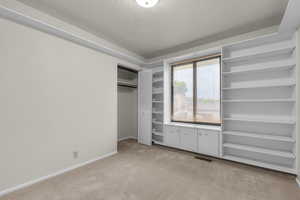 Unfurnished bedroom with light colored carpet, a textured ceiling, and a closet