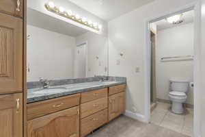 Bathroom featuring double vanity, a textured ceiling, light tile patterned flooring, and a shower stall
