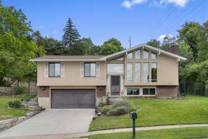 Split foyer home featuring stucco siding, brick siding, driveway, and a chimney