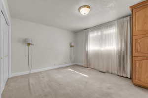 Unfurnished bedroom featuring light carpet, a textured ceiling, and a closet