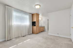 Unfurnished bedroom featuring a textured ceiling and light colored carpet