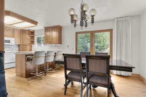 Dining space featuring a textured ceiling, light wood-style floors, and a chandelier