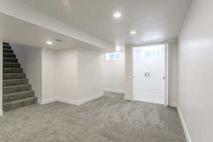 Basement featuring light carpet, recessed lighting, and stairs