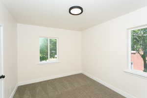 Carpeted spare room featuring baseboards