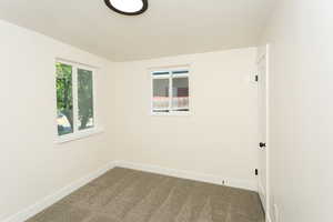 Carpeted spare room featuring baseboards and a textured ceiling