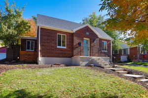 View of front of house featuring a shingled roof and a front yard