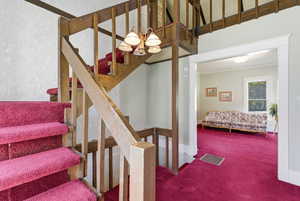 Stairs featuring a chandelier, crown molding, and carpet floors
