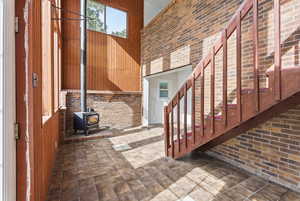 Stairs featuring brick wall, a wood stove, and a towering ceiling