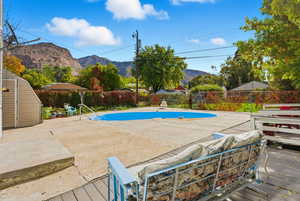 View of pool with a fenced backyard, a shed, a deck with mountain view, and a patio