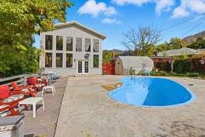 View of swimming pool with a deck, an outdoor structure, french doors, and a patio area