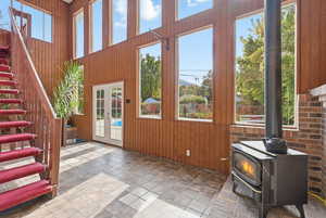 Entryway with wood walls, a wood stove, french doors, stairway, and stone finish floors