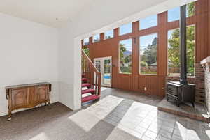 Doorway to outside with a wood stove, carpet flooring, and stairway