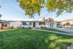 Ranch-style home featuring a front yard, brick siding, and french doors