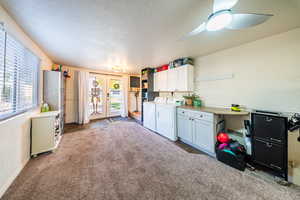 Kitchen with french doors, white cabinetry, carpet flooring, a textured ceiling, and washing machine and dryer
