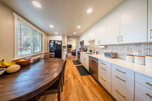 Kitchen with light wood-style flooring, white cabinets, stainless steel appliances, recessed lighting, and decorative backsplash