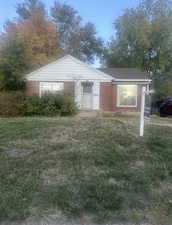 View of front of home with brick siding and a front lawn