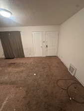 Unfurnished room featuring a textured ceiling and carpet floors