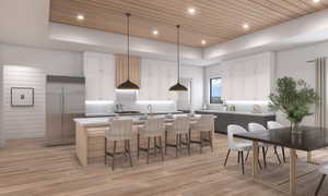 Dual tone kitchen with a wooden tray ceiling, dual tone cabinets, a center island with sink, tasteful backsplash, and stainless steel built in refrigerator