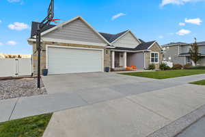Craftsman inspired home featuring stone siding, concrete driveway, an attached garage, a gate, and covered porch
