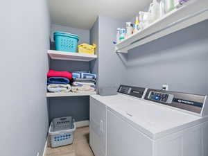Laundry area featuring light tile patterned floors and washer and clothes dryer