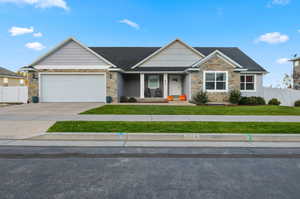 Craftsman-style home with stone siding, covered porch, concrete driveway, and an attached garage