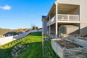 View of side of property featuring a vegetable garden, a patio, a fenced backyard, a residential view, and a storage unit