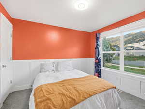 Bedroom with carpet floors, a wainscoted wall, a mountain view, and a decorative wall
