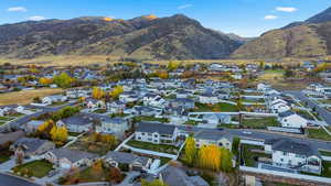 Aerial view of property and surrounding area featuring nearby suburban area and a mountainous background