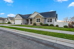 View of front of house featuring stone siding, concrete driveway, a porch, a garage, and a shingled roof