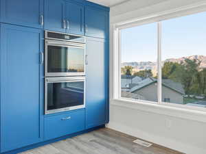 Kitchen featuring blue cabinets, double oven, a mountain view, and light wood finished floors