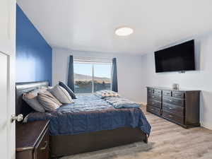 Primary bedroom with light wood-type flooring and baseboards