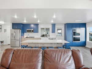 Kitchen featuring blue cabinetry, open floor plan, a kitchen island, stainless steel appliances, and light wood finished floors
