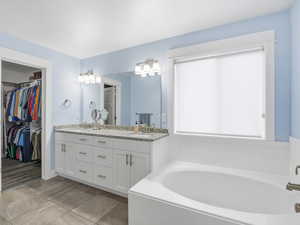 Bathroom featuring a bath, double vanity, and a spacious closet