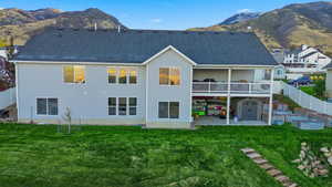Back of house featuring a patio, a mountain view, a fenced backyard, and a shingled roof