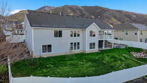 Rear view of house with a fenced backyard, a patio area, a mountain view, a balcony, and a shingled roof