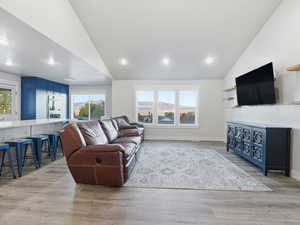 Living room with lofted ceiling, light wood-style flooring, and recessed lighting