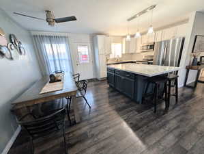 Kitchen with dark cabinetry, decorative backsplash, white cabinetry, decorative light fixtures, and a center island