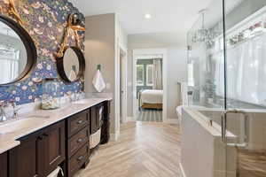 Bathroom featuring a chandelier, a stall shower, double vanity, a freestanding bath, and connected bathroom