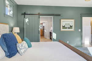 Bedroom featuring a barn door, wood finished floors, and connected bathroom