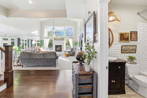Living area with a glass covered fireplace, tile walls, stairs, hardwood / wood-style floors, and a chandelier