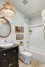 Full bath featuring vanity, tile walls, washtub / shower combination, and light wood-type flooring