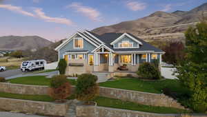 Craftsman inspired home with covered porch, a mountain view, a front lawn, and driveway