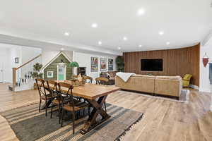Dining space featuring light wood-style flooring, recessed lighting, wooden walls, stairway, and an accent wall
