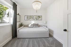 Carpeted bedroom with baseboards and a chandelier
