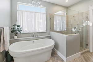 Bathroom featuring a freestanding tub, a stall shower, and wood finished floors